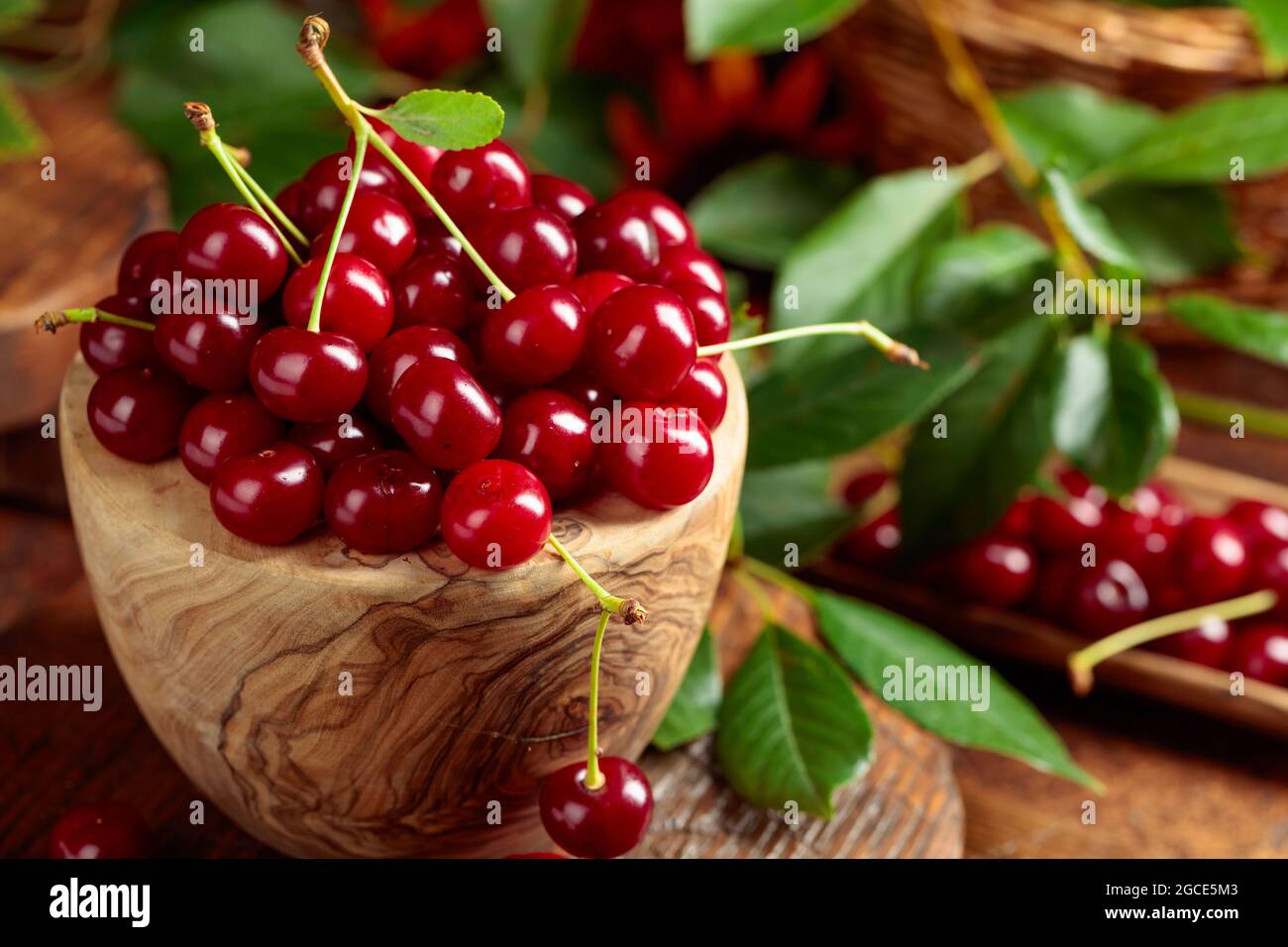 Ripe red cherries in a wooden dish on a brown table Stock Photo - Alamy