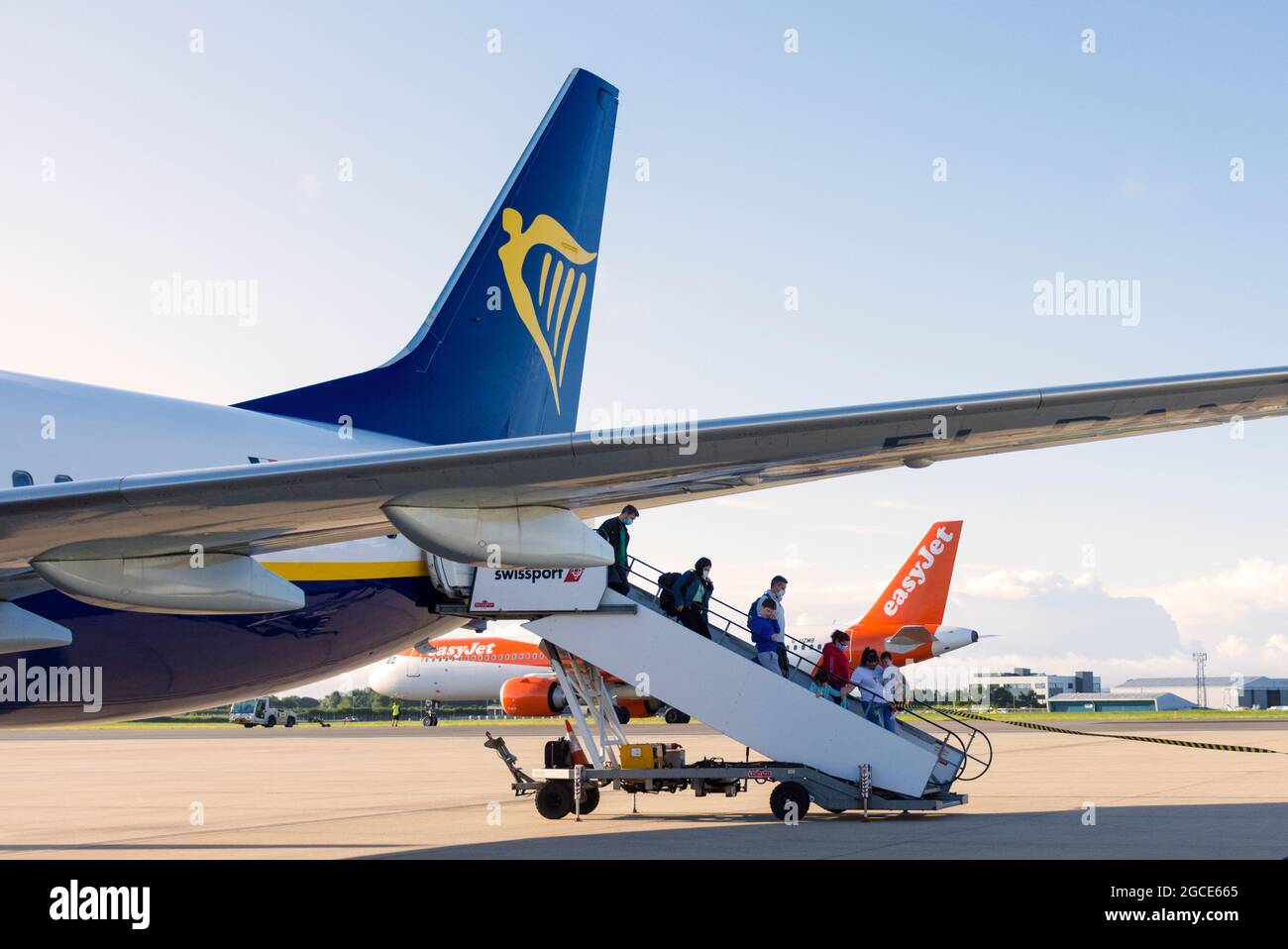 Passengers disembark from Ryanair flight as Easyjet aircraft prepares for takeoff at Bristol Airport, England, UK Stock Photo