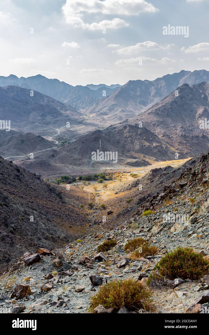 Hajar Mountains and Wadi Ghargur landscape view with transmission towers seen from Copper Hike Summit, barren, rocky mountains in Hatta, UAE. Stock Photo