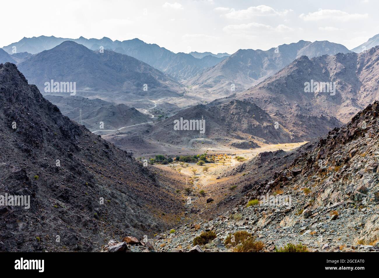 Hajar Mountains and Wadi Ghargur landscape view with transmission towers seen from Copper Hike Summit, barren, rocky mountains in Hatta, UAE. Stock Photo