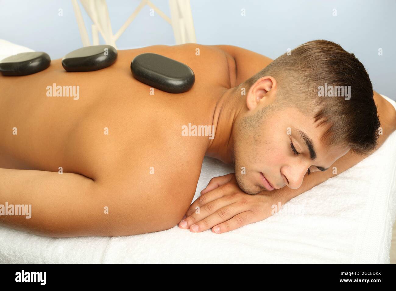 Young man relaxing with hot stones on back before massage Stock Photo -  Alamy