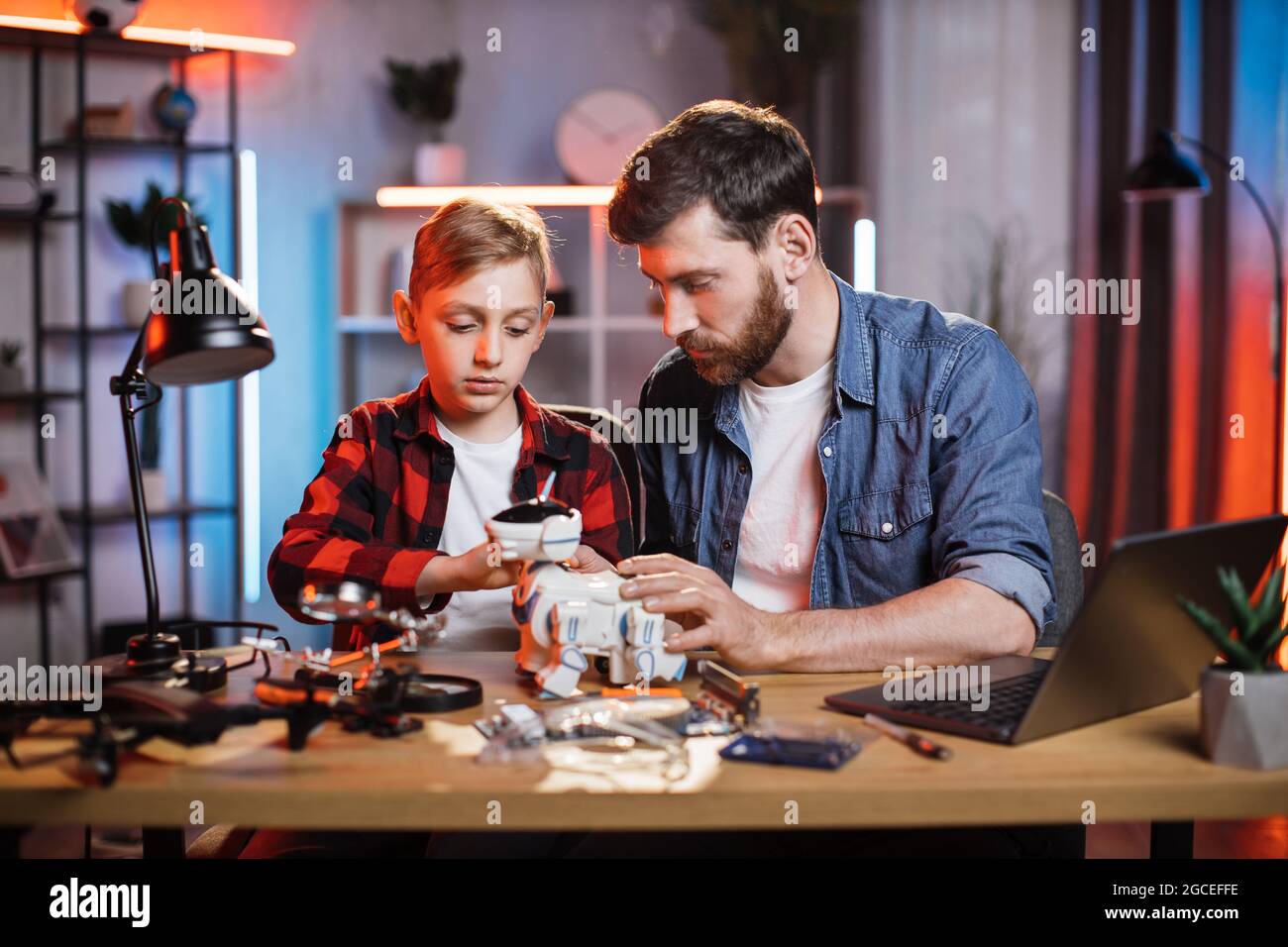 Caring father controlling repairing process of toy robot dog by his