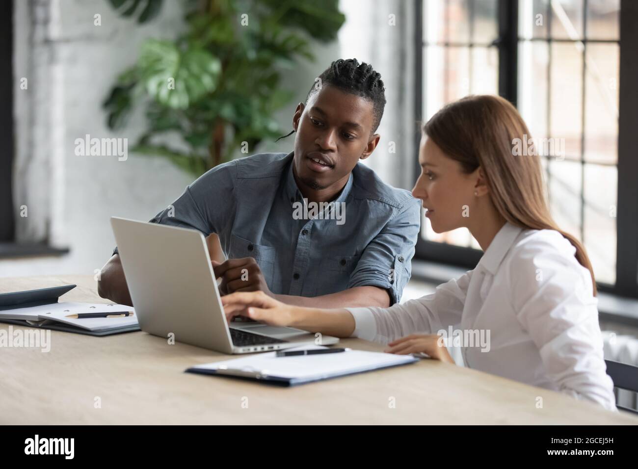 Diverse employees work together on computer at meeting Stock Photo