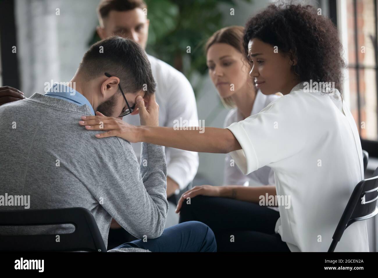 Caring ethnic woman support unhappy male at counseling Stock Photo
