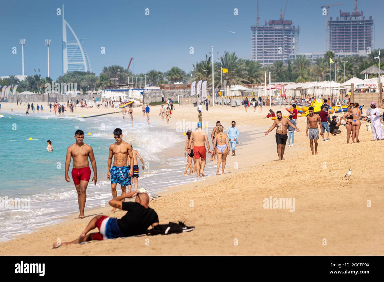 22 February 2021, Dubai, UAE: Crowds of people walk along the sandy beach of Jbr or Jumeirah Beach Residence. Vacationers swim and sunbathe Stock Photo