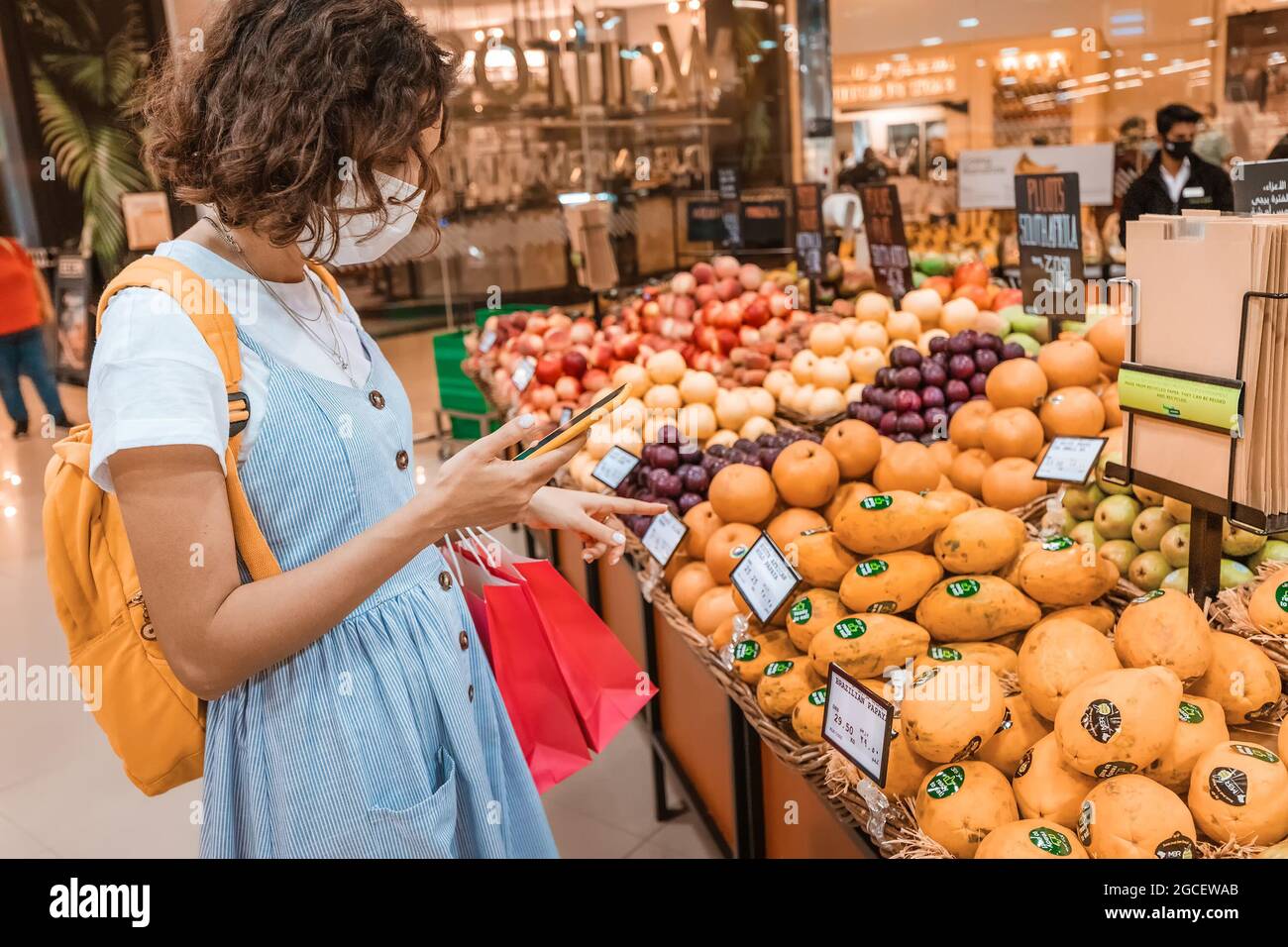 23 February 2021, Dubai, UAE: A woman wearing a medical mask during the coronavirus quarantine went to buy food and fruit in a supermarket and checks Stock Photo