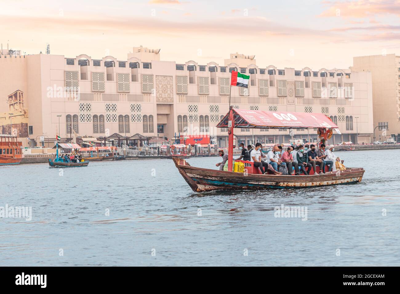 23 February 2021, Dubai, UAE: Abra Dhow wooden boat by RTA transport passengers wearing face masks from one bank of the Dubai Creek to the other Stock Photo