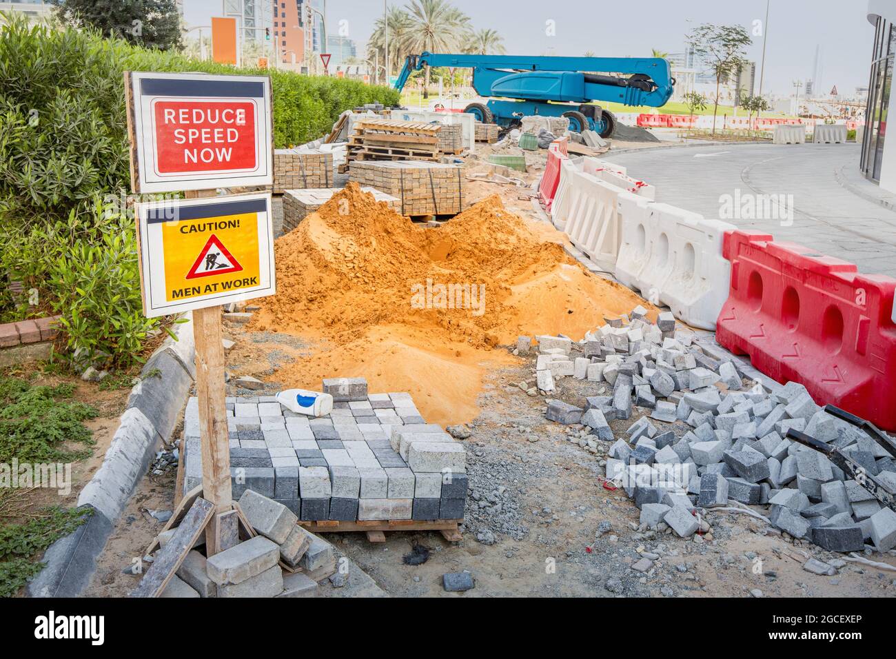 Improvement of sidewalks and laying of tiles at the construction site near the highway. Safety at work Stock Photo