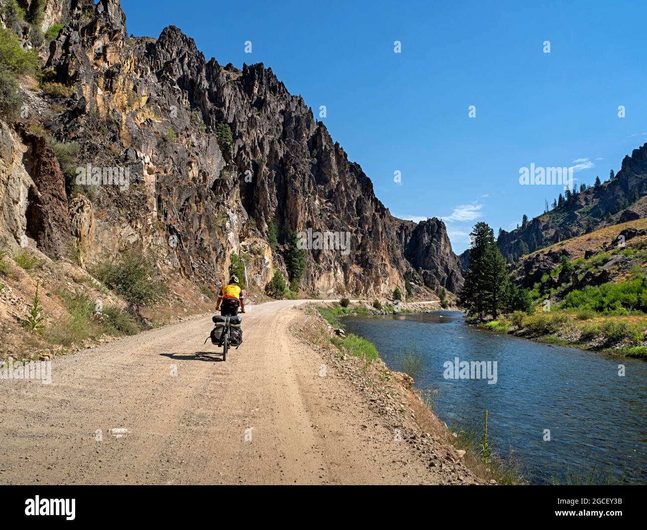 ID00826-00...IDAHO - Cyclist on the Middle Fork Road, passing  beneigth impressive cliffs along the Middle Fork of the Boise River. Stock Photo