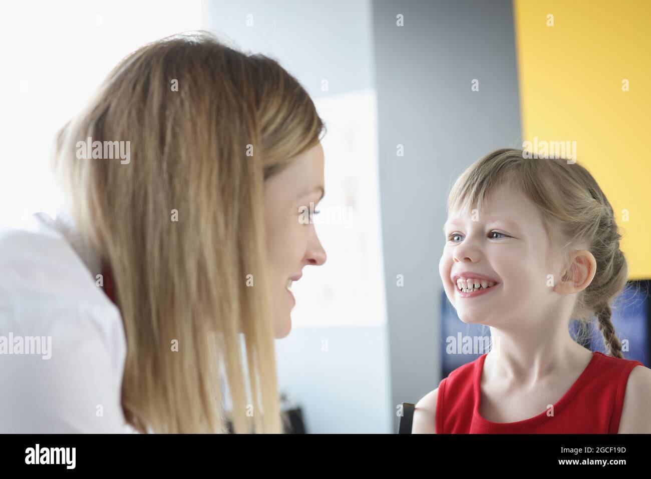 Woman speech therapist is engaged in speech with little girl Stock Photo