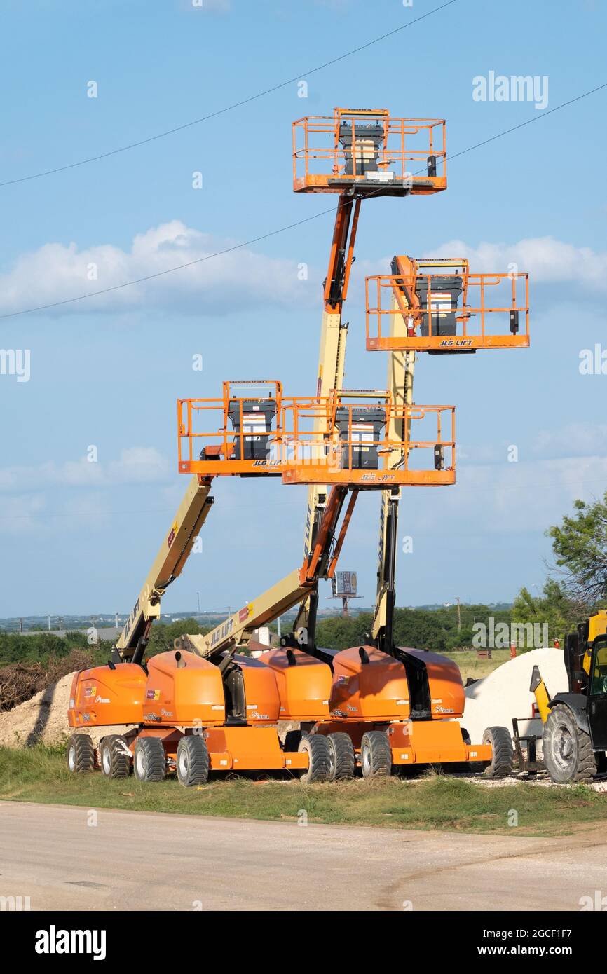 Four construction boom manlifts used for elevating construction workers safely above ground level Georgetown, Texas USA Stock Photo