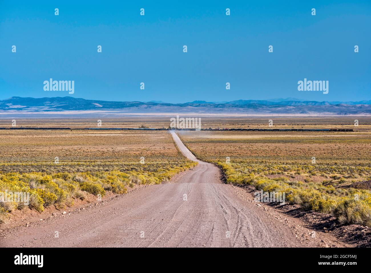 Freight train crossing Mountain Spring Road in settlement of Lund, Escalante Desert, Great Basin Desert, near Cedar City, Utah, USA Stock Photo