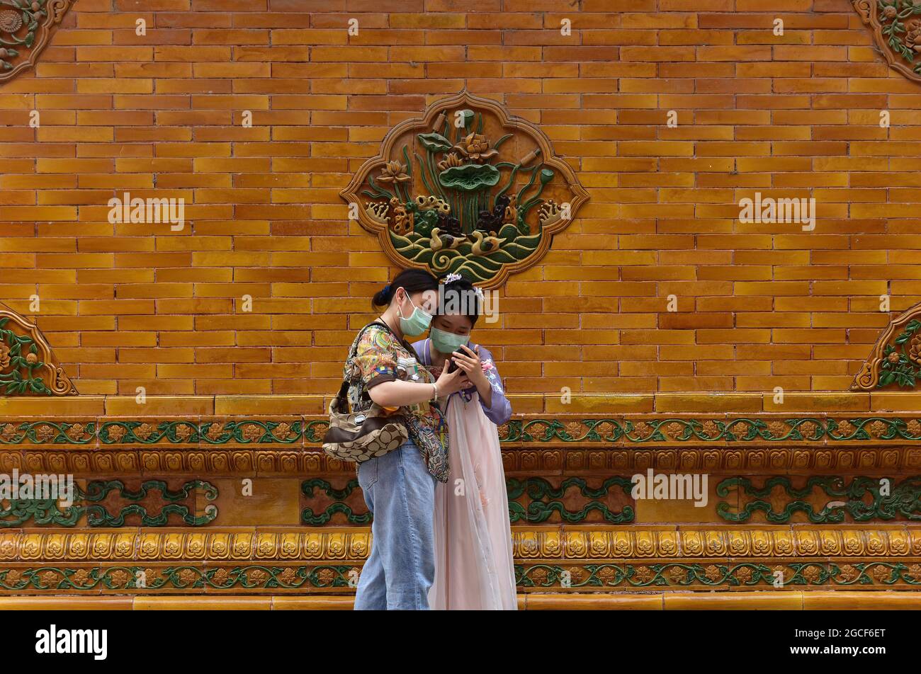 Beijing, China. 08th Aug, 2021. Women wearing face masks as a preventive measure against the spread of covid-19 use a mobile phone at the Forbidden City in Beijing. President Xi Jinping said on Thursday that China will provide a total of 2 billion doses of COVID-19 vaccines to the world this year, in the latest effort to honor its commitment to make vaccines a global public good by ensuring vaccine accessibility and affordability. Credit: SOPA Images Limited/Alamy Live News Stock Photo