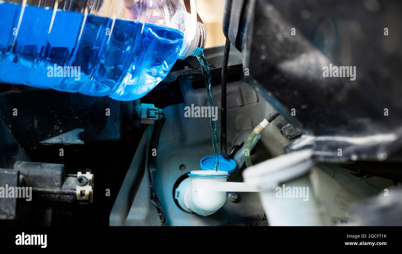 Auto mechanic pours windshield washer fluid into the car Stock Photo
