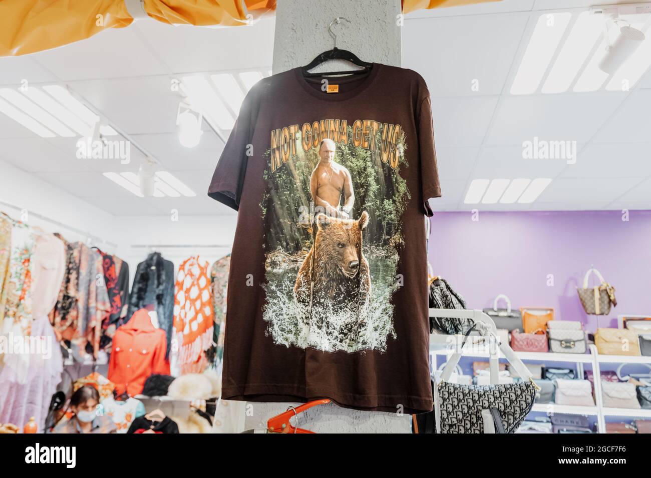 26 February 2021, UAE, Dubai: T-shirt with pucture of president Vladimir Putin riding on a wild bear is for sale in russian souvenir shop Stock Photo