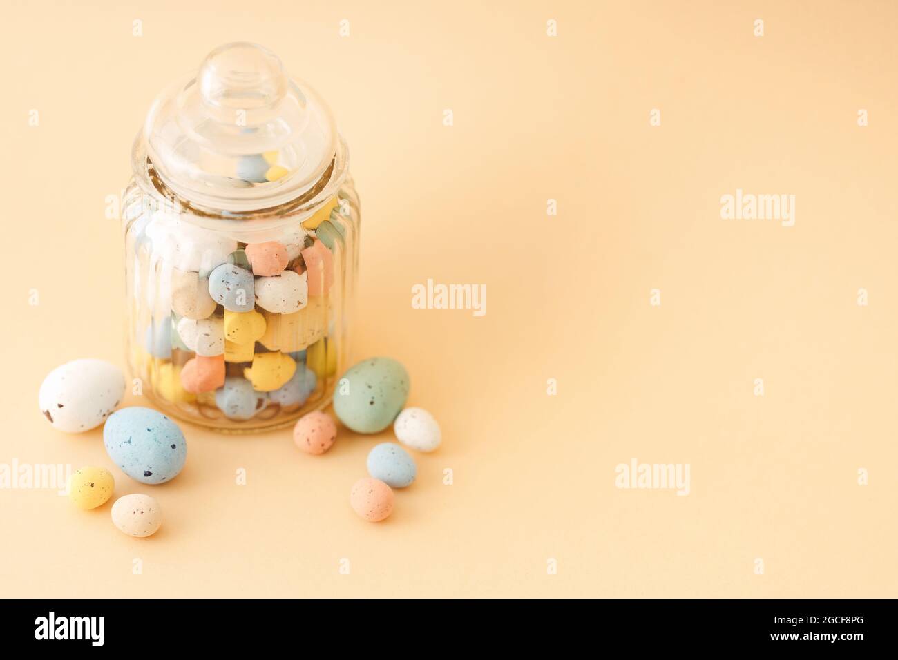 Multicolor Easter candy eggs on beige background. Stock Photo