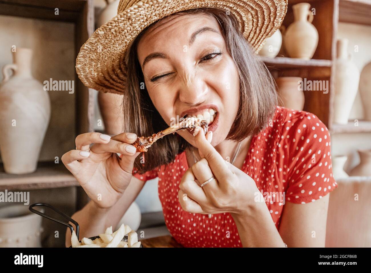 Woman with a strong appetite nibbles the bones of a fried chicken leg. The concept of overeating and gluttony and delicious fatty food Stock Photo