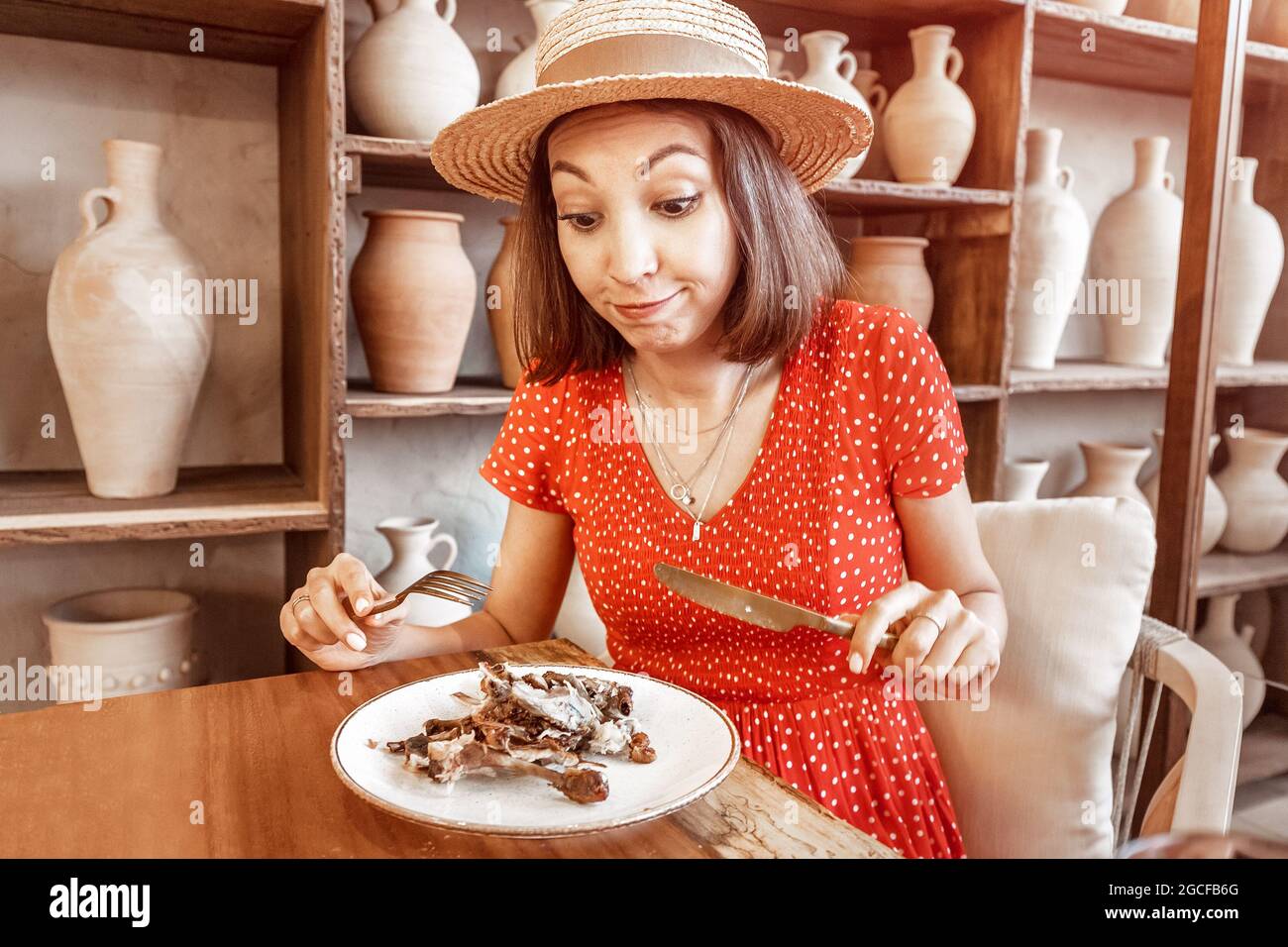 Woman with a strong appetite finishes the meal in restaurant. Bones of a fried chicken in a plate. The concept of overeating and gluttony and deliciou Stock Photo