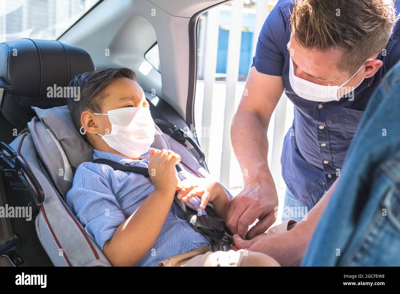 father putting seat belt on his son in the car seat Stock Photo