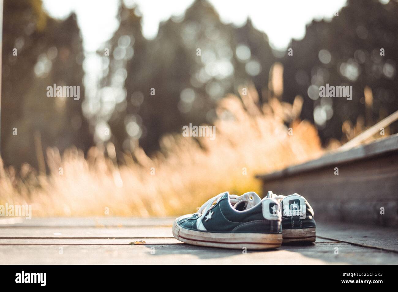 Chester, UK - 17th July 2021: Converse trainers sat on a porch in the wilderness whilst camping in glamping tents Stock Photo