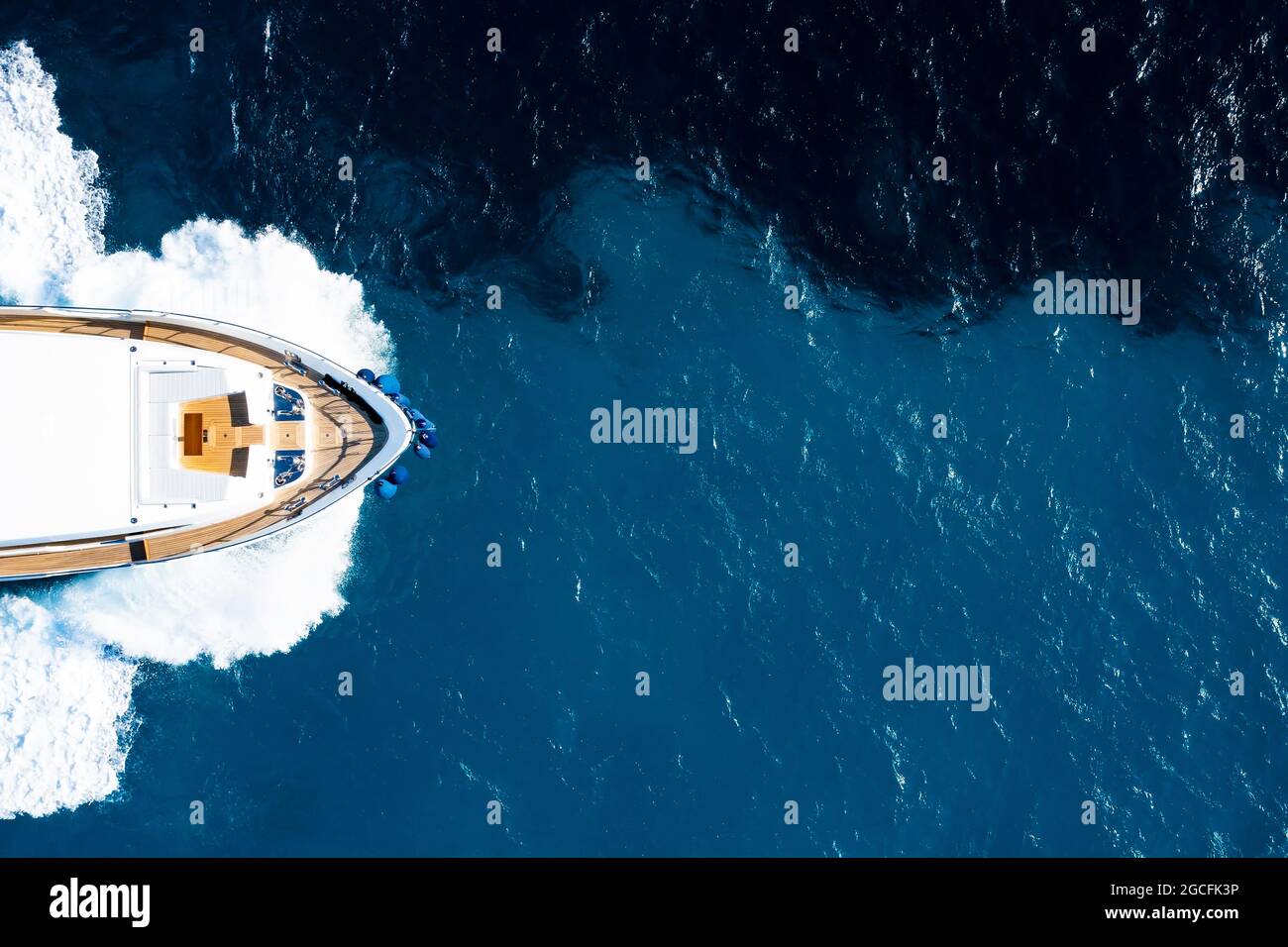 View from above, stunning aerial view of a deck of a luxury yacht cruising on a blue water creating a wake. Costa Smeralda, Sardinia, Italy. Stock Photo