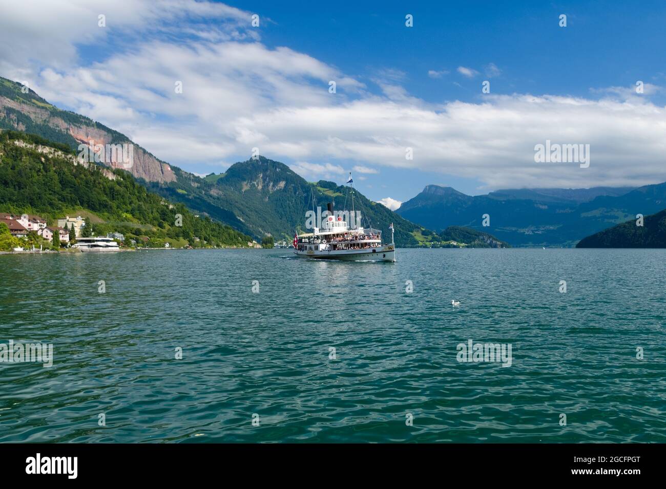 Sunny view of the old wheeled boat sailing near the village of Weggis facing the lake of Luzern with the Swiss mountains in the background Stock Photo
