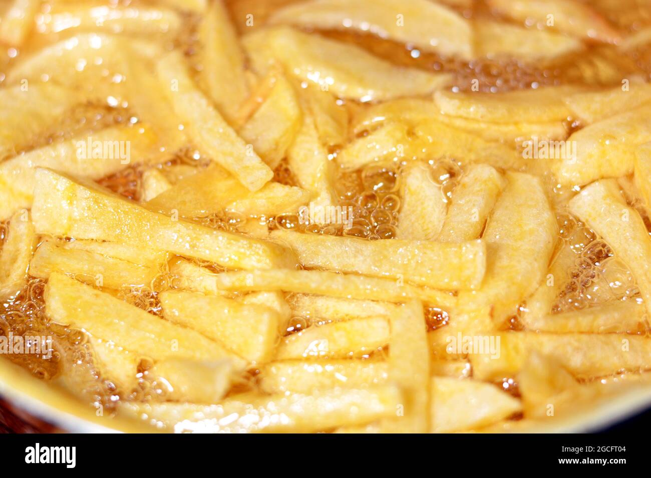 Closeup of French fries potatoes frying in boiling hot oil in a deep