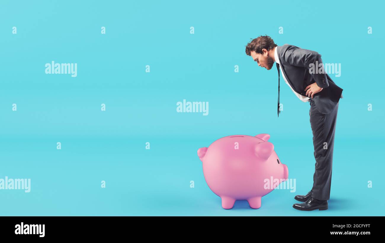 Man looks inside the piggy bank looking for money Stock Photo - Alamy