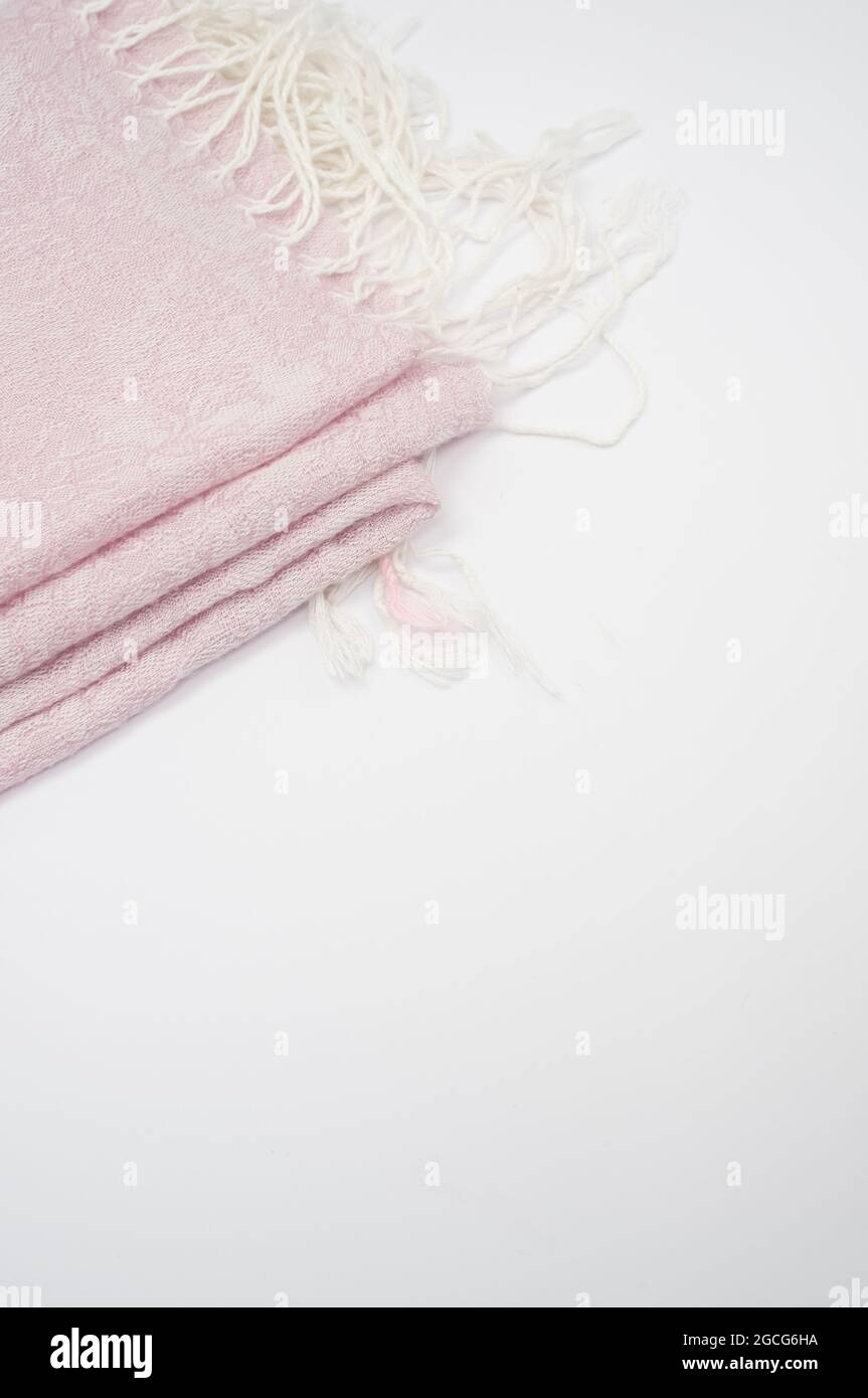 A closeup shot of a folded pale pink scarf with white tassels with a copy space Stock Photo