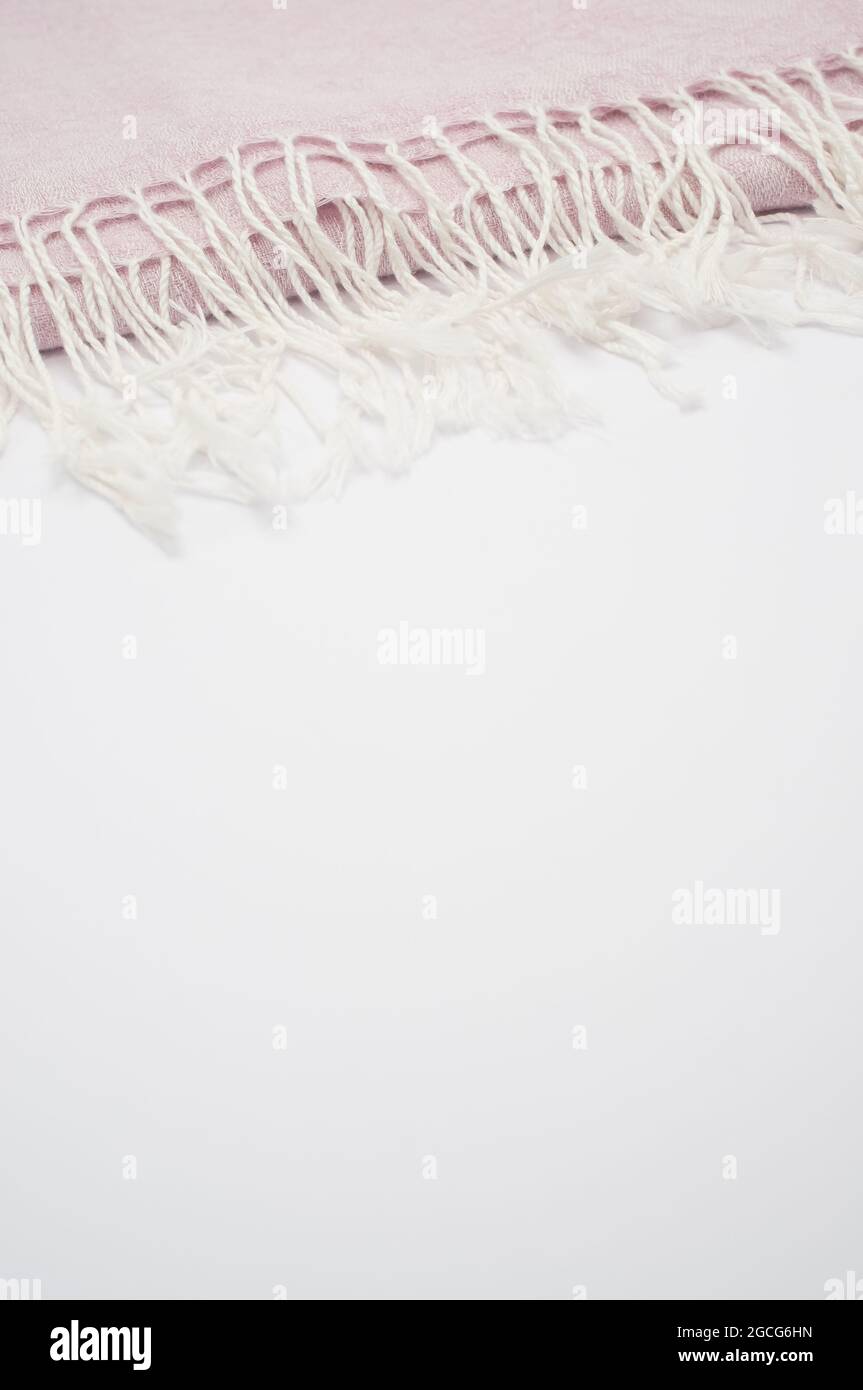 A closeup shot of a folded pale pink scarf with white tassels with a copy space Stock Photo
