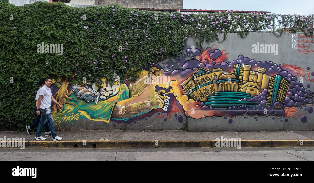 Two men walking past wall art in San Jose, Costa Rica Stock Photo