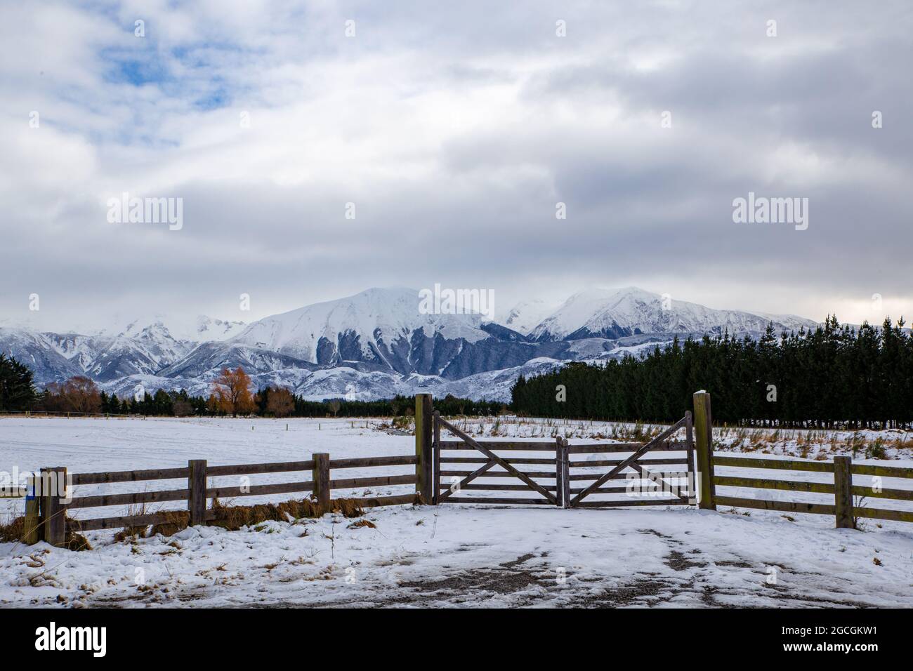 The morning after a snow fall looking out over rural farm land, foothills and mountains with a wooden farm fence, Springfield, Canterbury, New Zealand Stock Photo