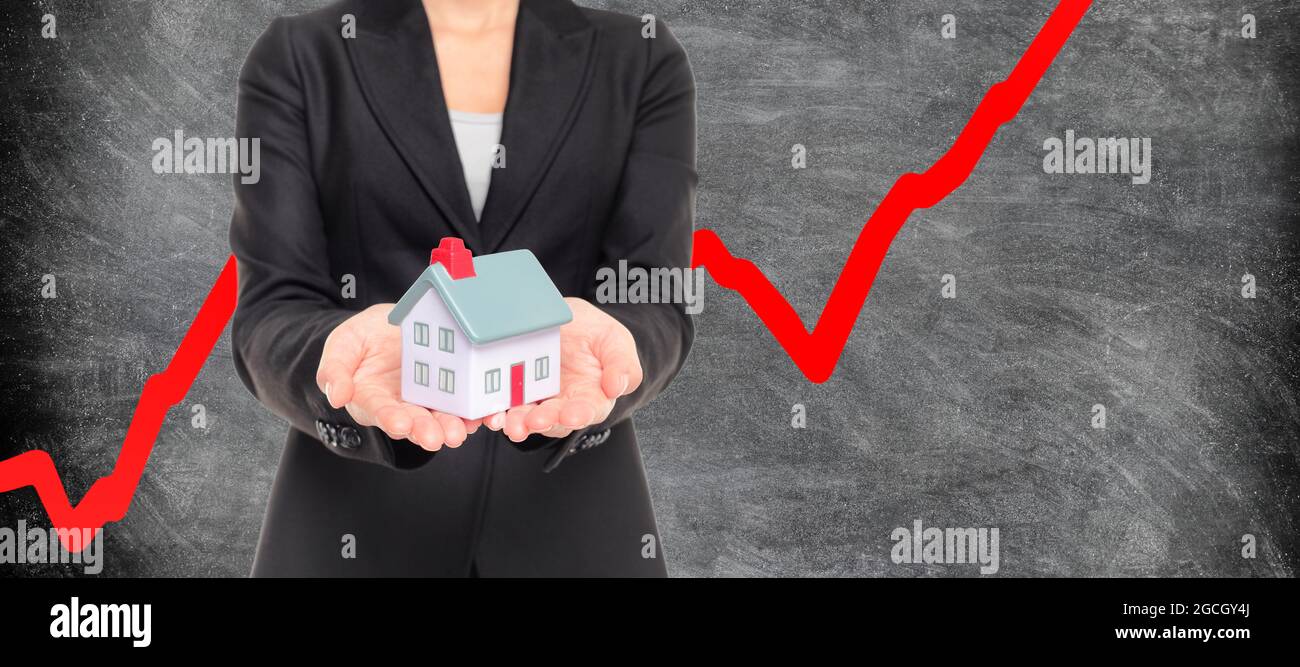 Real estate housing market bubble inflation. Realtor holding miniature house with red chart going up in blackboard background. Panoramic banner Stock Photo