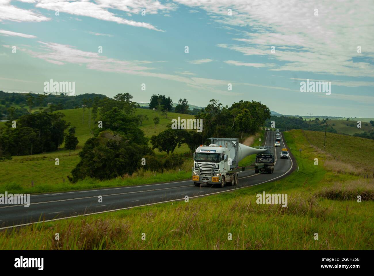 Wind Turbine Blade being transported to Mt Emerald Wind Farm Nth Qld Australia. Road passing through green farming country Atherton Tablelands. Stock Photo