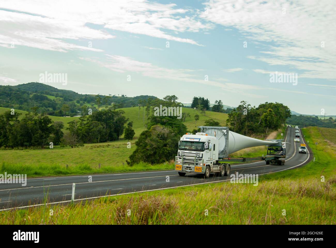 Wind Turbine Blade being transported to Mt Emerald Wind Farm Nth Qld Australia. Road passing through green farming country Atherton Tablelands. Stock Photo