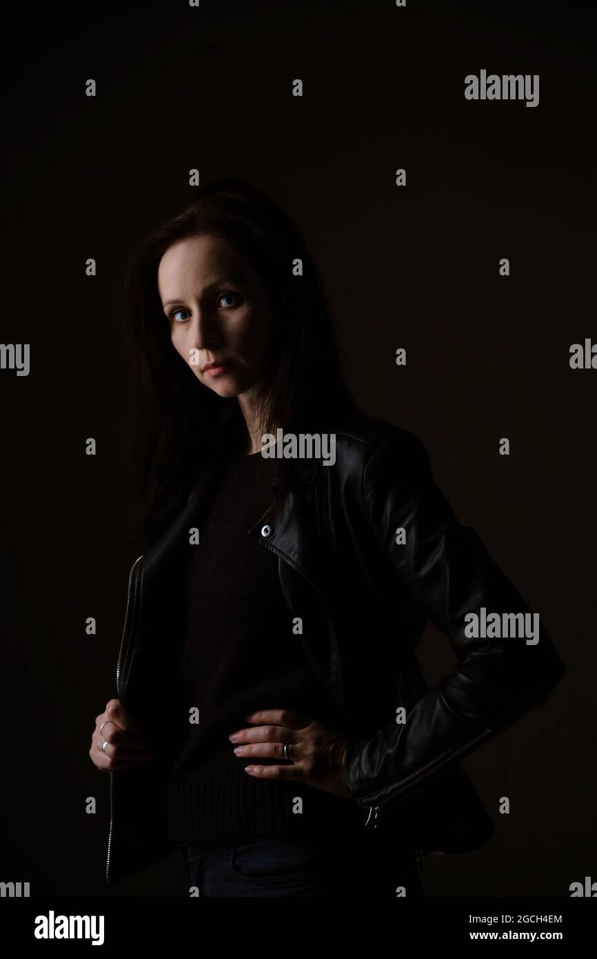 portrait of an attractive young brunette woman in a black leather ...