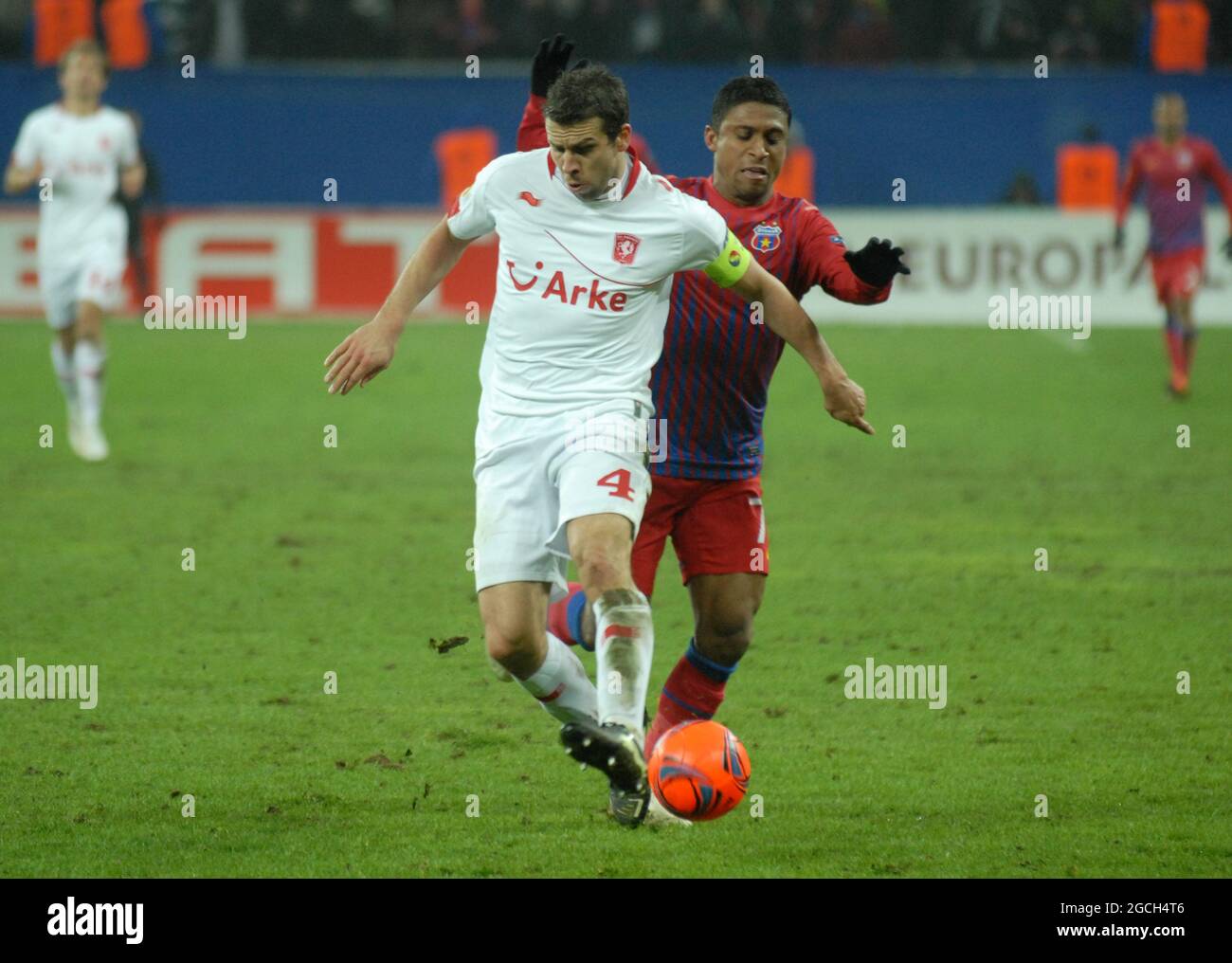 BUCHAREST, ROMANIA - FEBRUARY 16, 2012: Peter Wisgerhof (L) of Twente and Leandro Tatu (R) of FCSB pictured in action during the first leg of the 2011/12 UEFA Europa League Round of 32 game between FCSB and FC Twente at National Arena. Stock Photo
