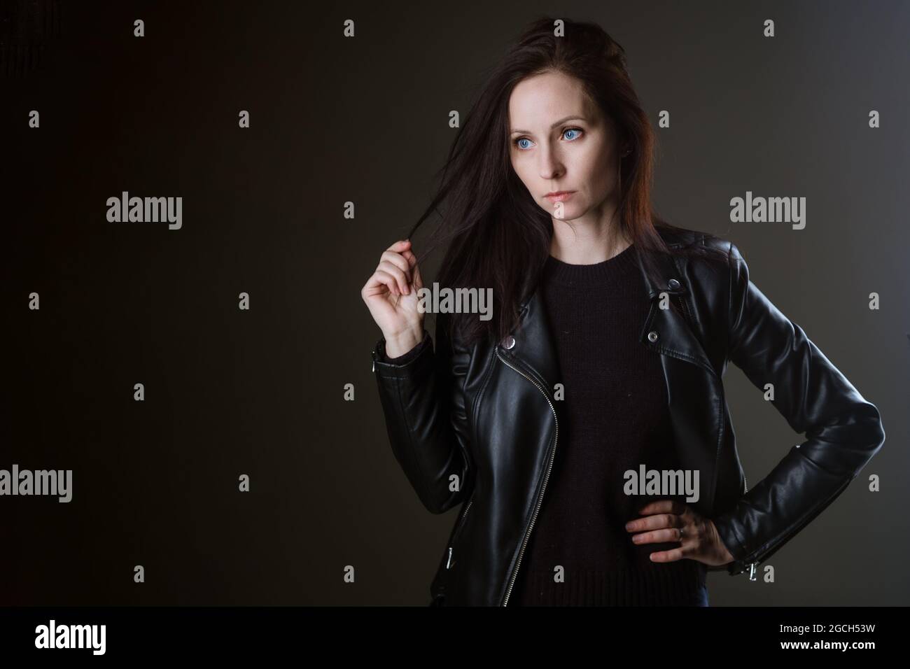 portrait of an attractive young brunette woman in a black leather ...
