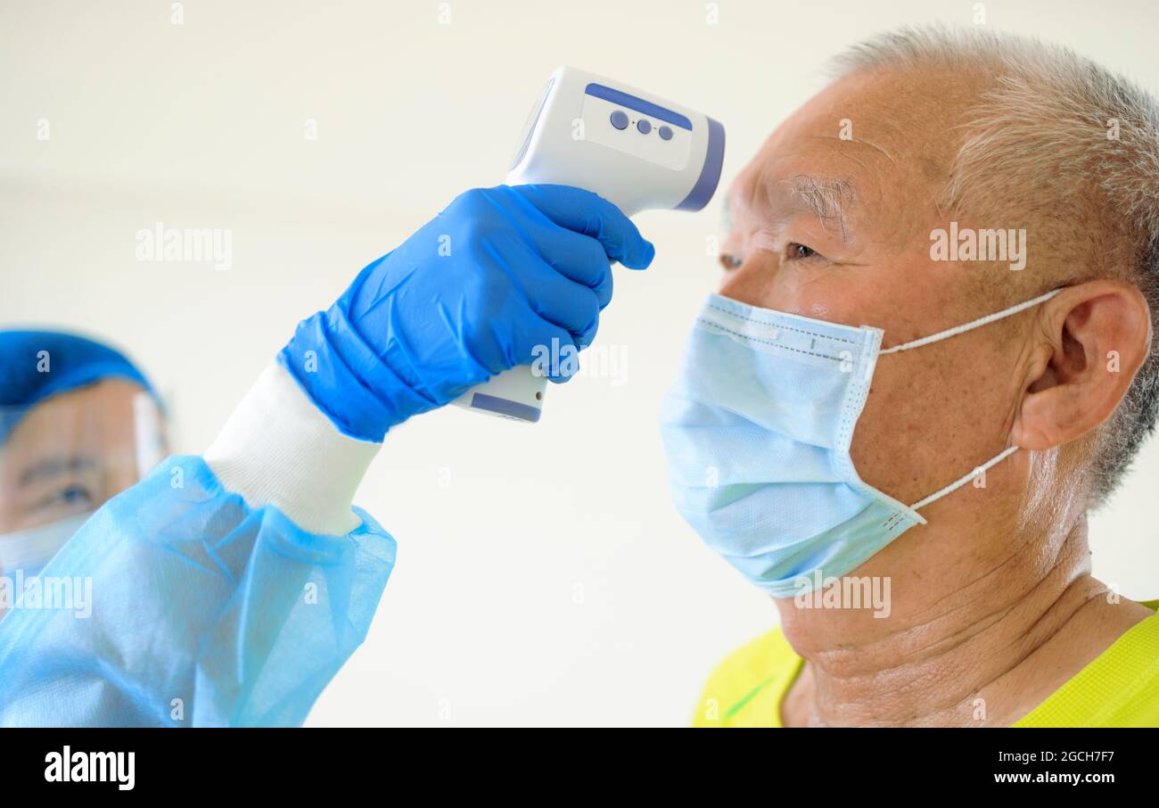 Nurse use an Infrared thermometer equipment to check the temperature on the forehead of senior