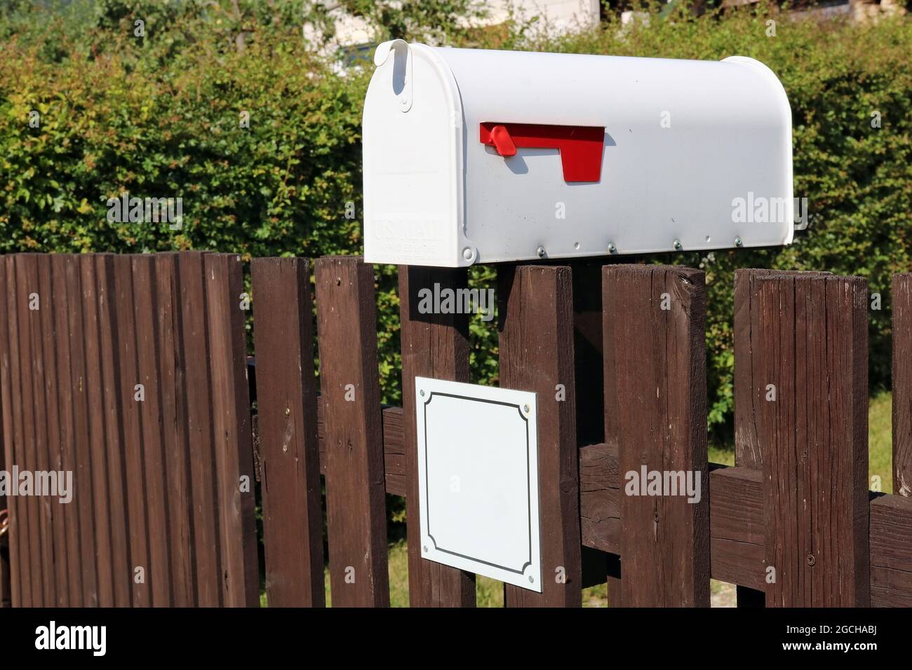 White metal mailbox mounted on a rustic  fence Stock Photo