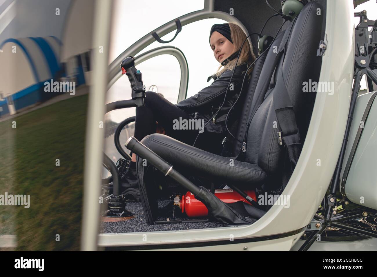 Confident tween girl sitting on co-pilot seat in helicopter Stock Photo
