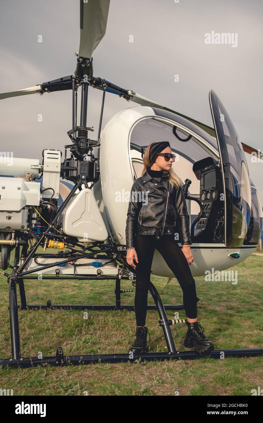 Teenage girl in black clothes and sunglasses looking into distance near  helicopter Stock Photo - Alamy