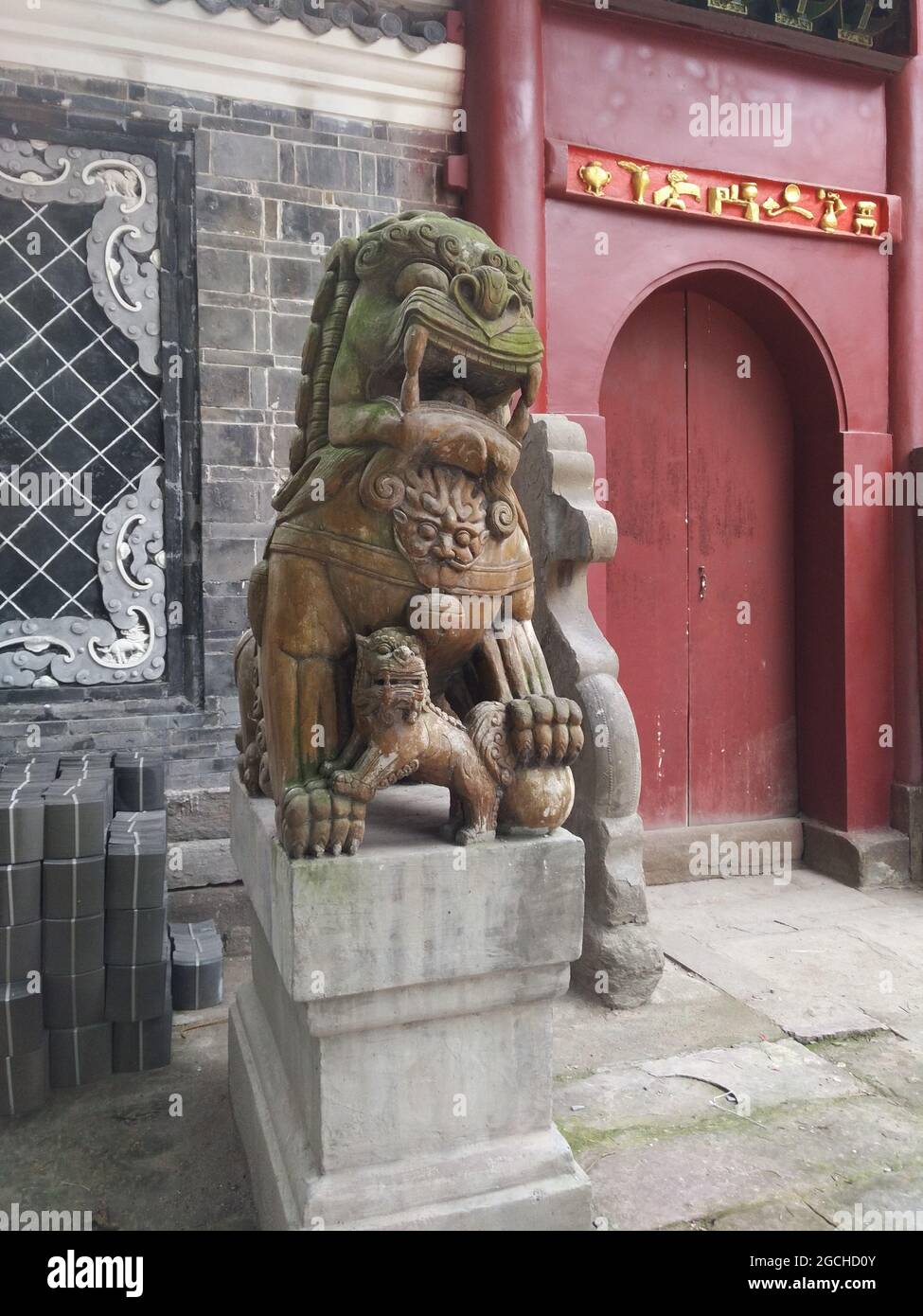 A stone lion dog guardian statue and cub on a post at Hui Guang Temple in ancient Lizhuang District of Yibin City Stock Photo