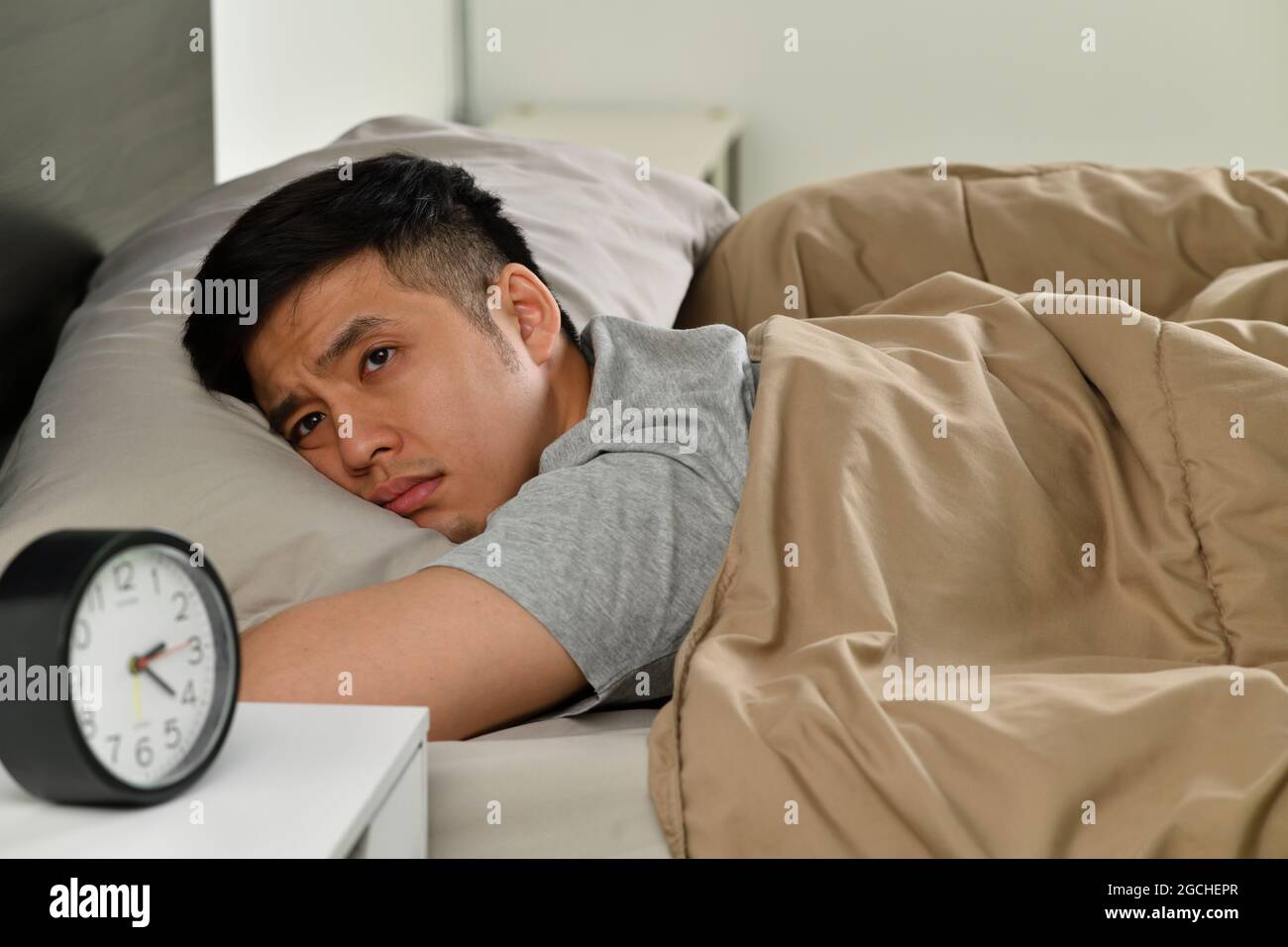 Depressed young Asian man lying in bed cannot sleep from insomnia Stock ...