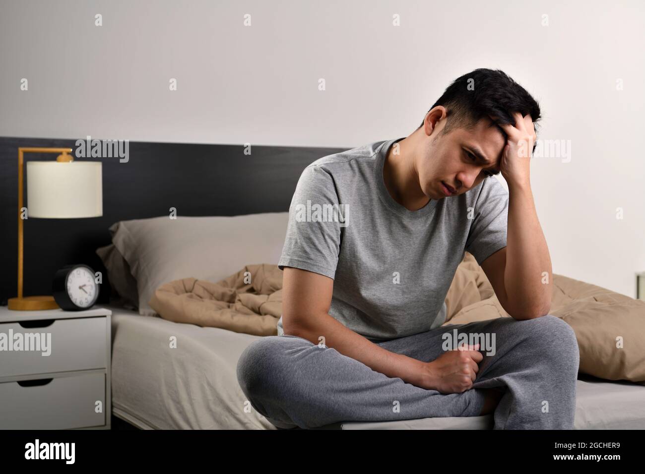 Depressed young Asian man sitting in bed cannot sleep from insomnia ...