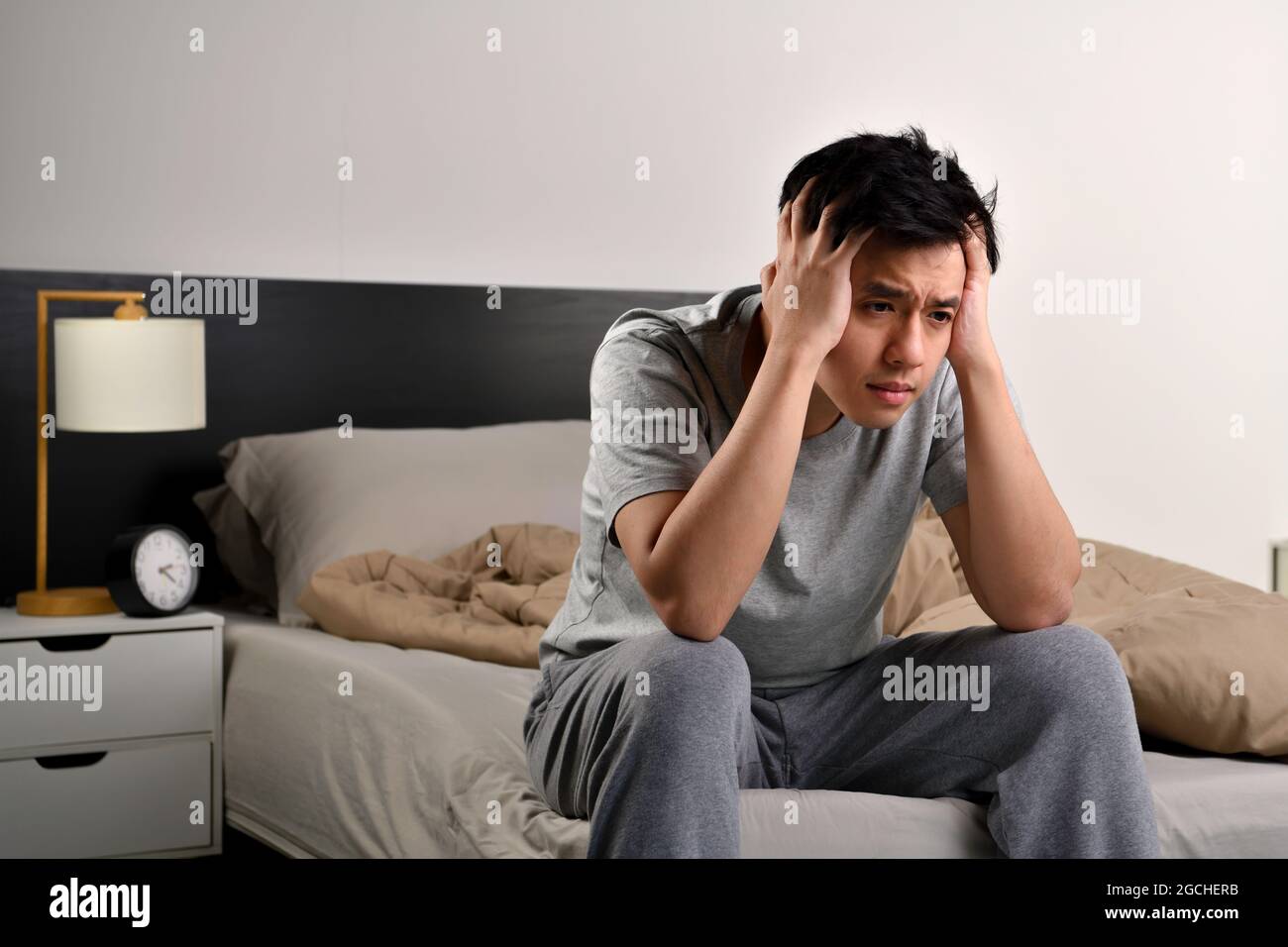 Depressed young Asian man sitting in bed cannot sleep from insomnia ...
