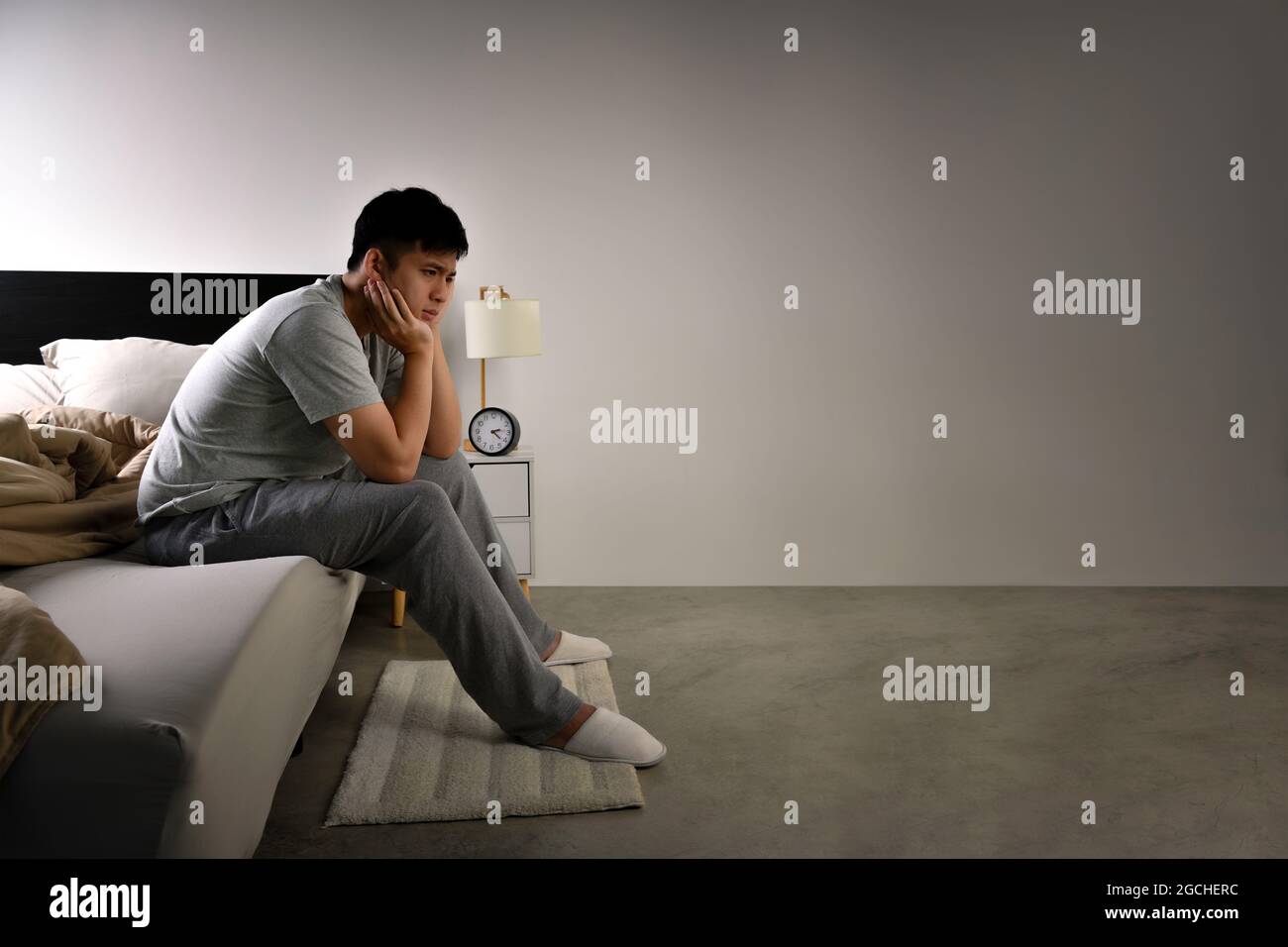 Depressed young Asian man sitting in bed cannot sleep from insomnia ...