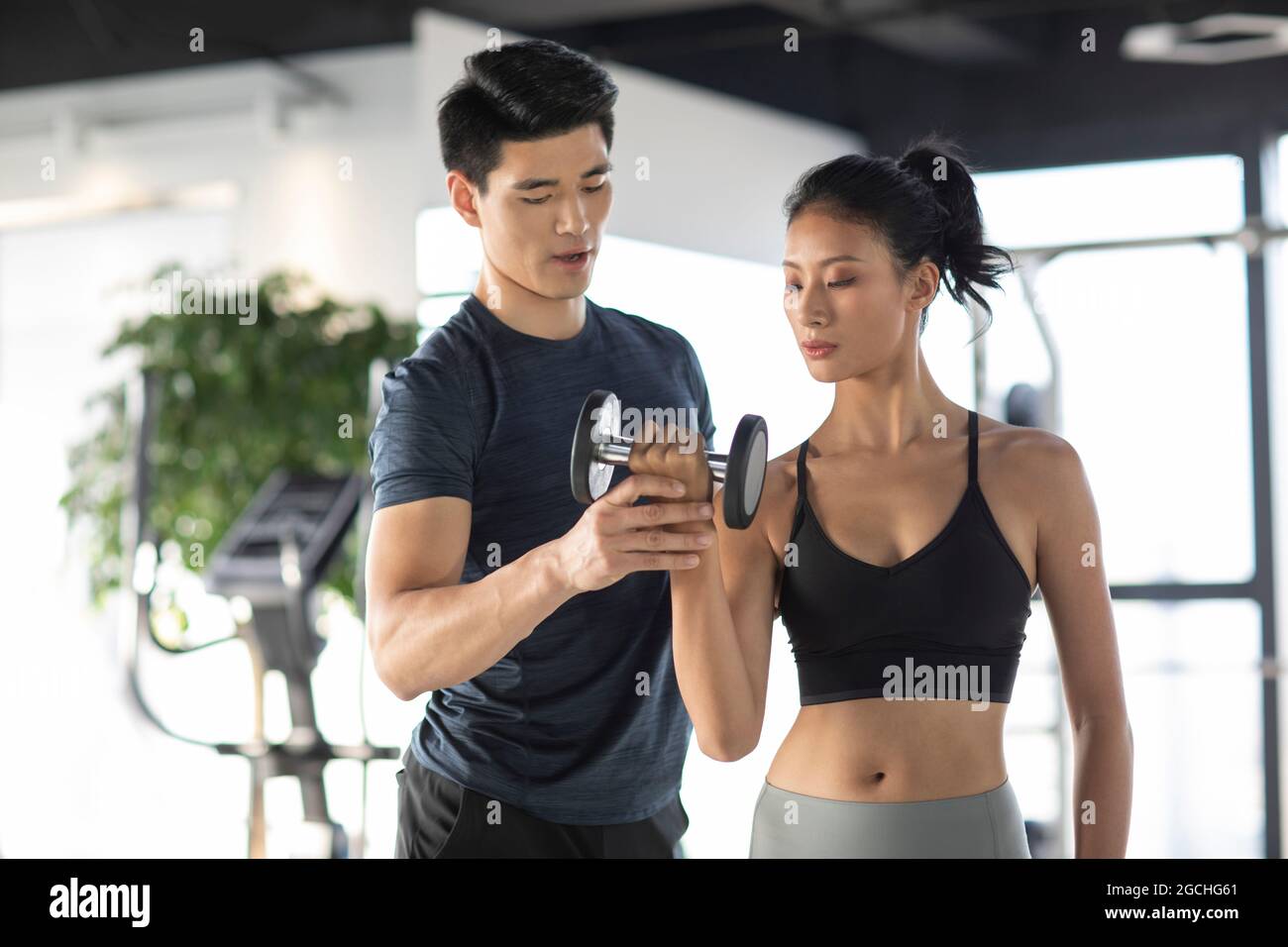Young woman working out with personal trainer at gym Stock Photo - Alamy