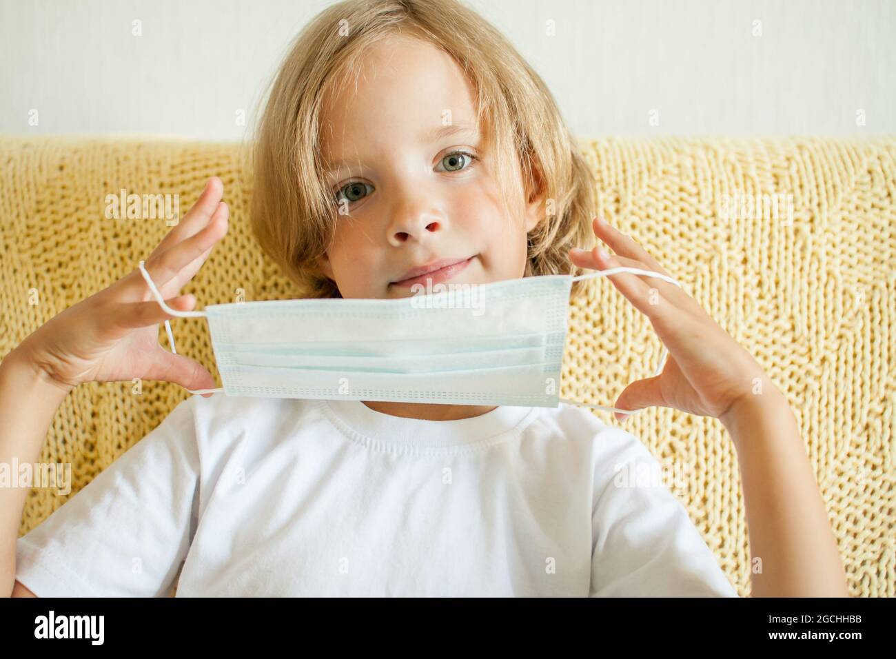 Portrait of a little girl putting on a medical protective mask ...