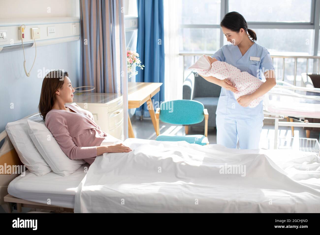 Female nurse helping new mom taking care of newborn baby Stock Photo